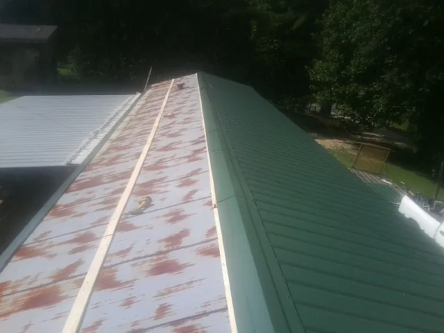 Old rusted panels beside newly installed green metal roofing — Wind Damage Roof Repair by Roofing Brothers in North