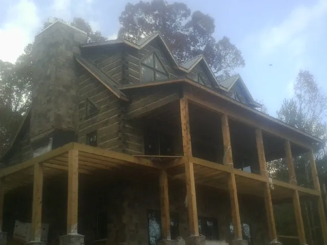 Stone chimney and dormers on a large log home with a timber porch in North