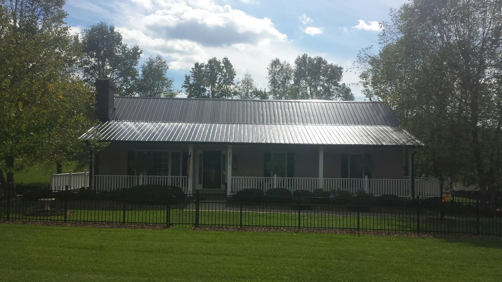 Gray metal roof on a brick ranch with a full width front porch — Gutter Guard Installation work by our crew in North