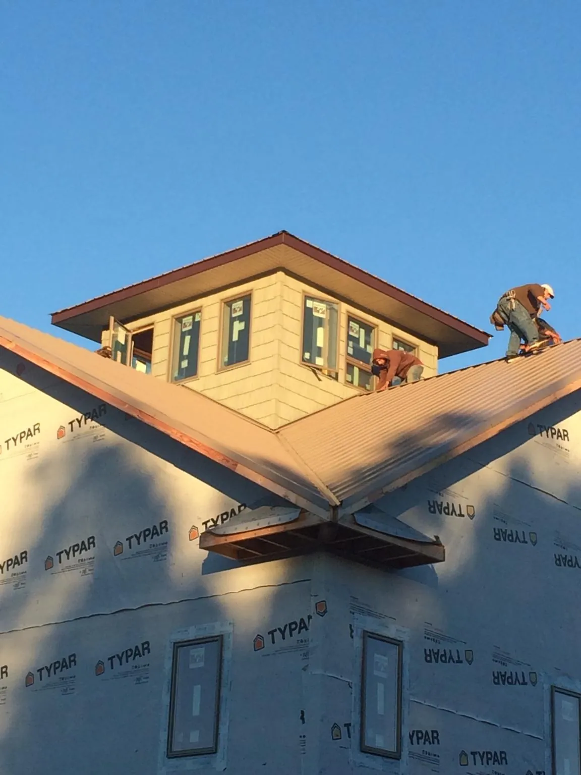 Roofers working around a rooftop cupola on a new metal roof at sunset — Roof Waterproofing in North by Roofing Brothers